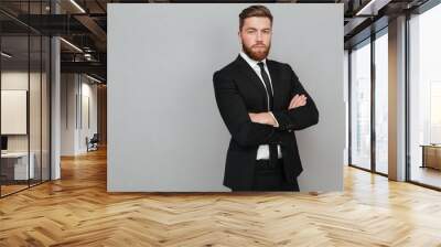 Confident young businessman in suit standing with arms folded Wall mural