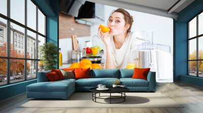 cute charming woman making juice and eating oranges Wall mural