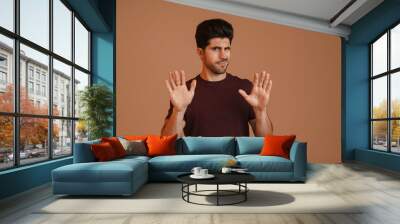 Displeased unshaven young man showing stop gesture at camera Wall mural