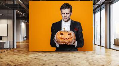 Displeased zombie man holding pumpkin and looking aside Wall mural