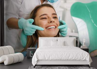 European young woman smiling while looking at mirror in dental clinic Wall mural