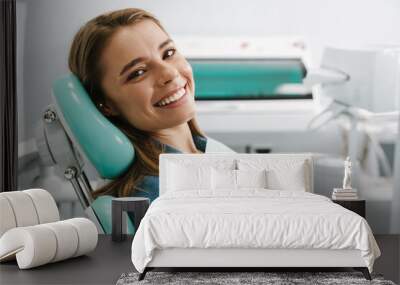 European young woman smiling while sitting in medical chair Wall mural