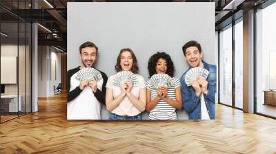 Excited group of friends looking camera holding money. Wall mural