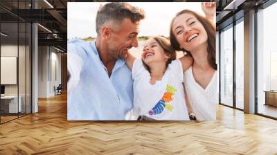 Family outdoors at the beach take a selfie by camera. Wall mural