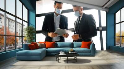 Focused brunette manager in face mask discussing contract with customer Wall mural