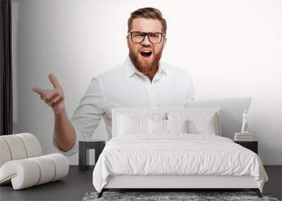 Frustrated man in eyeglasses holding laptop and gesturing with hand Wall mural