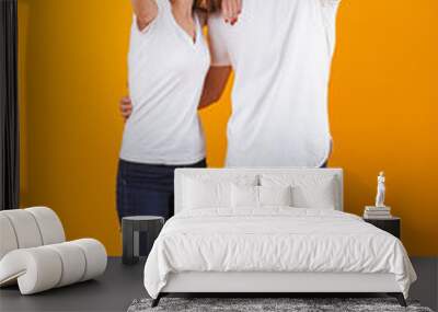 Full length photo of joyful couple smilings while standing, isolated over yellow background Wall mural