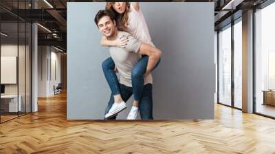 Full length portrait of a joyful man carrying girlfriend Wall mural