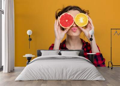 Funny playful woman holding halves of citrus fruits against eyes Wall mural