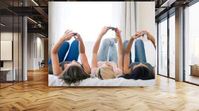 Girls lying on the bed and using smartphones Wall mural