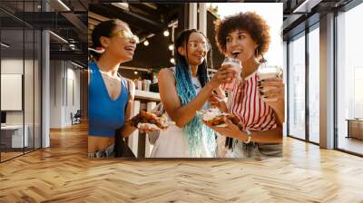 Group of african women eating bubble waffles in park Wall mural