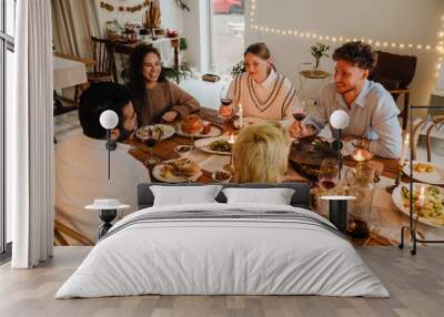 Group of cheerful friends having Christmas dinner together at home Wall mural