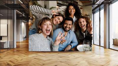 Group of cheerful friends taking selfie while dining in restaurant Wall mural