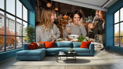 Group of friends drinking wine while dining in restaurant Wall mural