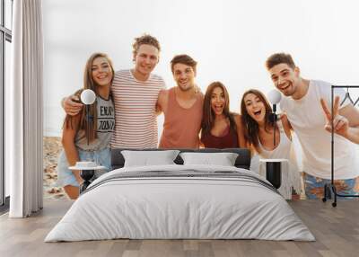 Group of happy friends standing at the beach together Wall mural