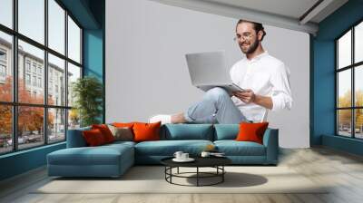 Handsome bearded man wearing glasses using laptop computer. Wall mural