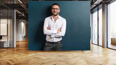 Handsome cheerful man standing over dark blue background Wall mural