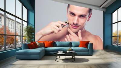 Handsome man shaving with electric razor Wall mural