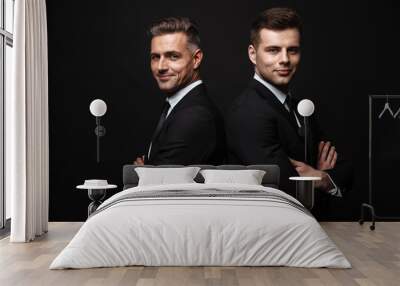 Handsome two adult business men posing isolated over black wall background. Wall mural