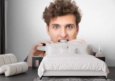 Handsome young man biting book over gray background Wall mural