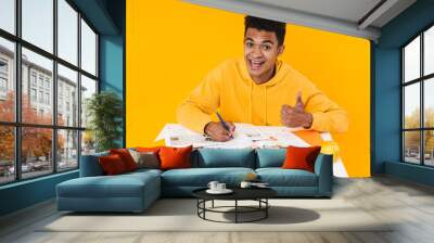 Happy african teenager boy studying while sitting at the desk Wall mural