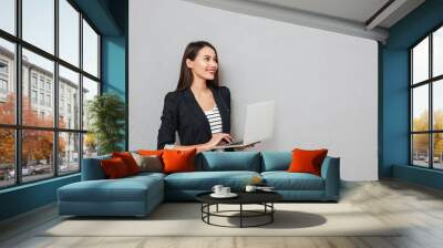 Happy asian business woman holding laptop computer and looking away Wall mural