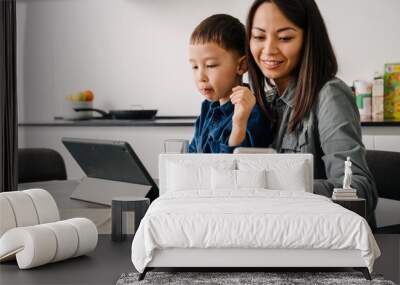 Happy asian woman using cellphone while having breakfast with her son Wall mural