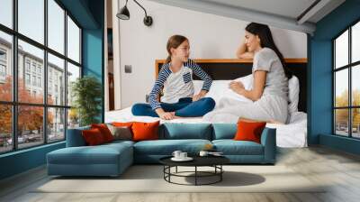 Happy beautiful mother and daughter talking while sitting on bed Wall mural