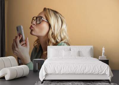 Happy beautiful woman holding and kissing her mobile phone Wall mural