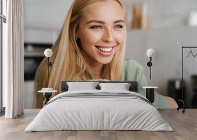 Happy blonde young woman smiling and looking aside Wall mural