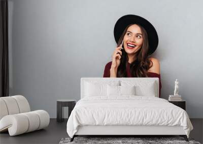 Happy brunette woman in sweater and hat talking by smartphone Wall mural