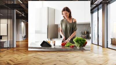 Happy casual middle aged woman cutting vegetables Wall mural