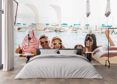 Happy family with children wearing sunglasses swimming in pool, with rubber ring during travel or vacation Wall mural