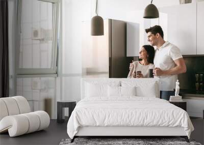 Happy lovely young couple holding cups Wall mural