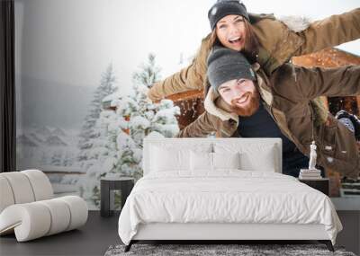 Happy man piggibacking his girlfriend and laughing in winter Wall mural