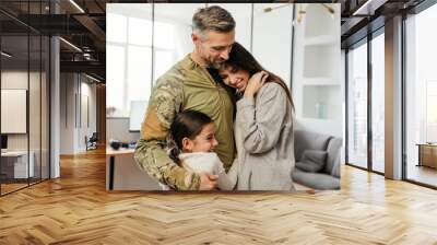 Happy masculine military man smiling and hugging his family indoors Wall mural