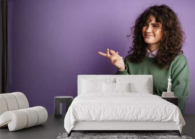 Happy puzzled curly girl smiling and gesturing with hand Wall mural