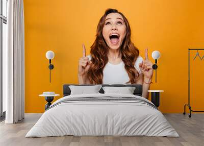 Happy screaming brunette woman in t-shirt pointing and looking up Wall mural