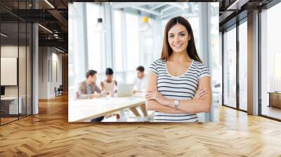 happy woman standing with arms crossed in office Wall mural