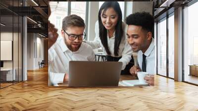 Happy young business colleagues using laptop computer. Wall mural