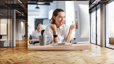 Happy young businesswoman sitting at her workplace Wall mural