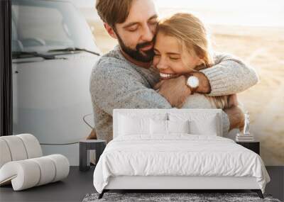 Happy young couple in love embracing while leaning on a car Wall mural