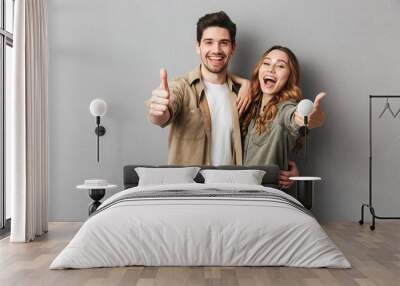 Happy young couple showing thumbs up Wall mural