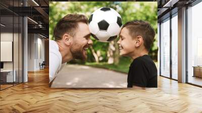 Happy young father have fun with his little son with football Wall mural