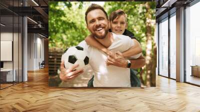 Happy young father have fun with his little son with football Wall mural