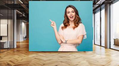 Happy young lady pointing. Wall mural