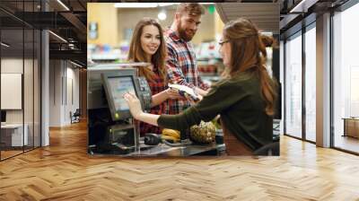 Happy young loving couple standing in supermarket Wall mural