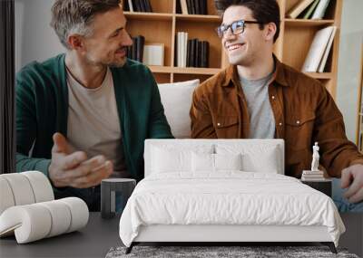 Happy young male gay couple talking while relaxing Wall mural