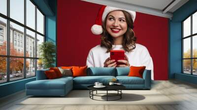 Happy young woman in christmas santa hat Wall mural