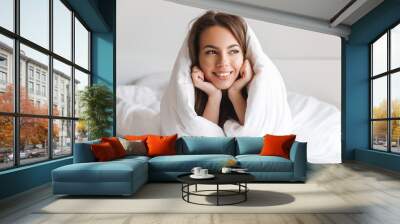 Happy young woman laying in bed covered Wall mural